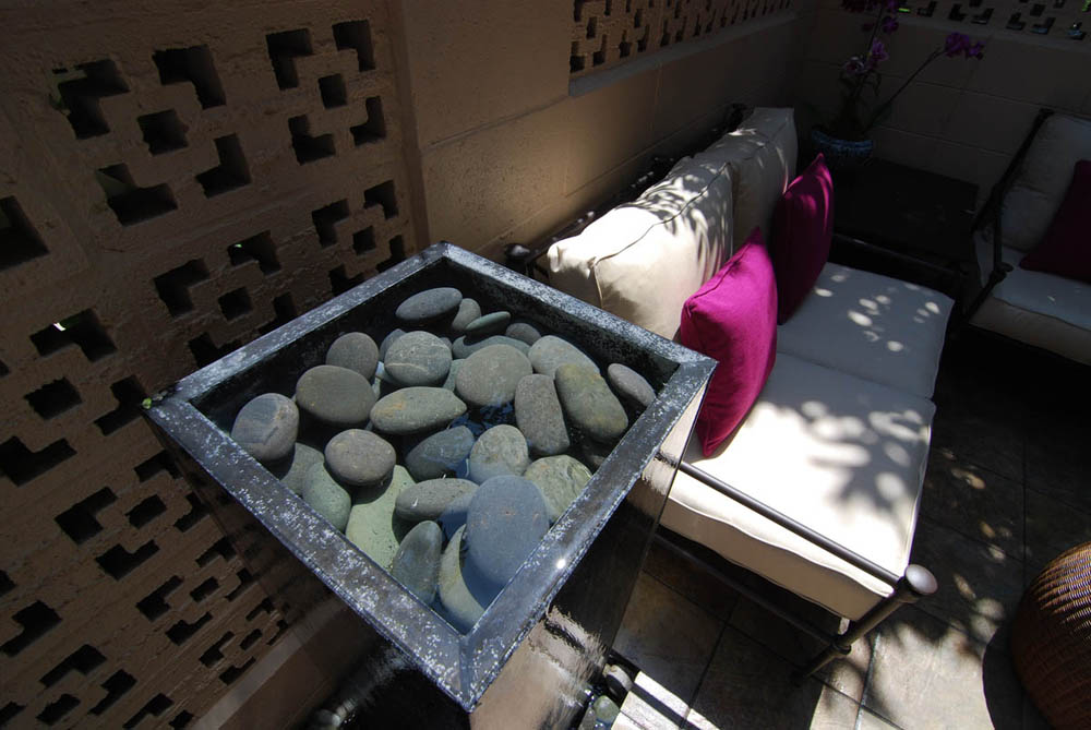 The water is pumped up through the center and flows down the sides. Back into a common water trough with beach pebbles.