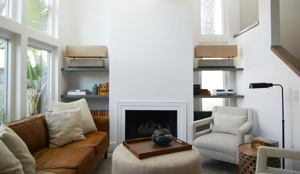 A modern living room with a minimalist fireplace. Putting artwork above the fireplace made the space feel small.